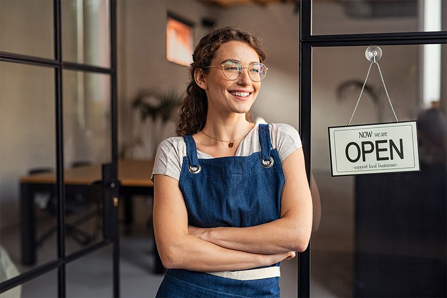 Business Insurance - Small Business Owner Standing At Cafe Entrance
